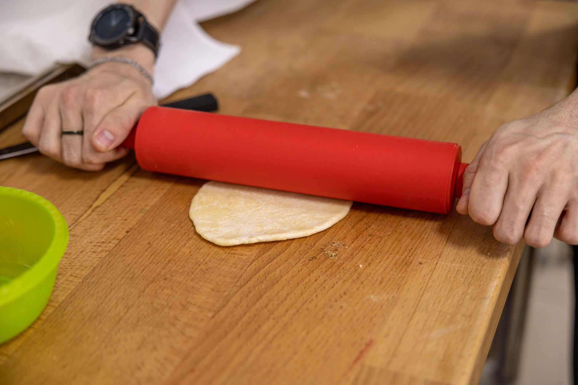 Close-up of a chef's hands rolling dough for Indian bread on a wooden surface